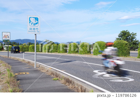 クルマとバイクが鳥取県境港市の米子鬼太郎空港沿いのメロディー道路を走る光景 119786126