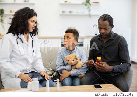 Doctor advises father and son about medication at home visit 119786148