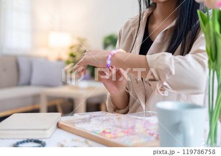 Young girl making handmade bracelets with fun and cheerfulness Young girl making handmade bracelets with fun and cheerfulness 119786758