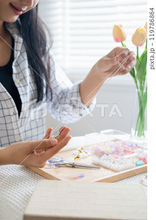 Young girl making handmade bracelets with fun and cheerfulness 119786864