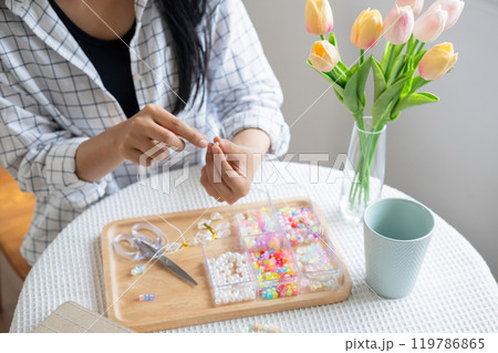 Young girl making handmade bracelets with fun and cheerfulness 119786865