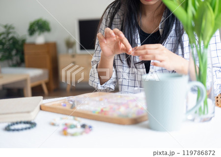 Young girl making handmade bracelets with fun and cheerfulness Young girl making handmade bracelets with fun and cheerfulness 119786872