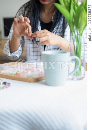 Young girl making handmade bracelets with fun and cheerfulness Young girl making handmade bracelets with fun and cheerfulness 119786873