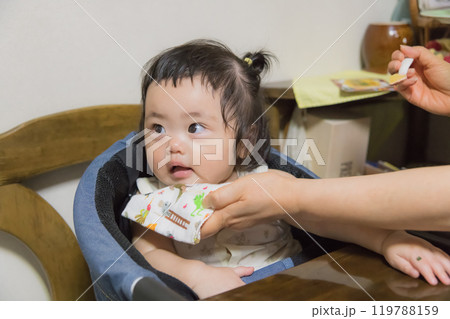 【離乳食を食べる髪を結んだ赤ちゃん】 119788159