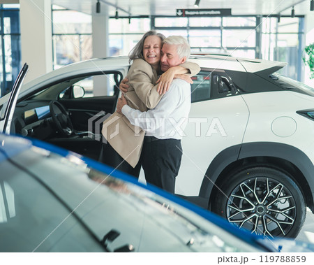 Mature Caucasian couple hugging. Elderly man and woman buying a new car.  119788859