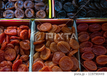 Orange and dark dried apricots in boxes for sale at the market, top view. Dried fruit, dried apricots as background. Orange and dark dried apricots in boxes for sale at the market, top view. Dried fruit, dried apricots as background. 119790449