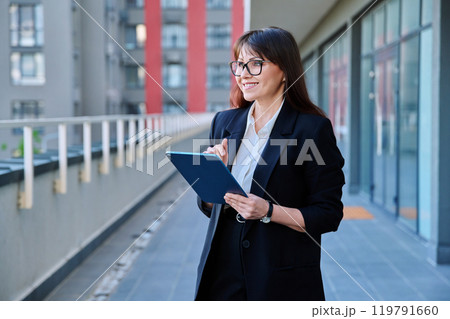 Mature woman manager agent using digital tablet for work, city background Mature woman manager agent using digital tablet for work, city background 119791660