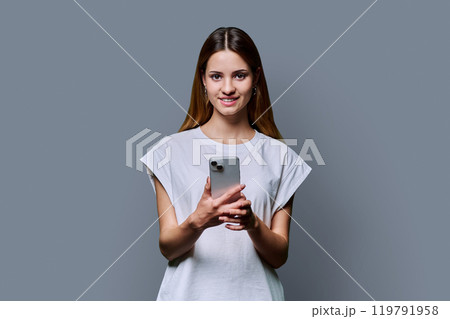 Young beautiful woman using smartphone on grey studio background Young beautiful woman using smartphone on grey studio background 119791958