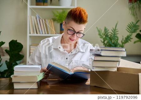 Woman with new books unpacked from cardboard box 119792096