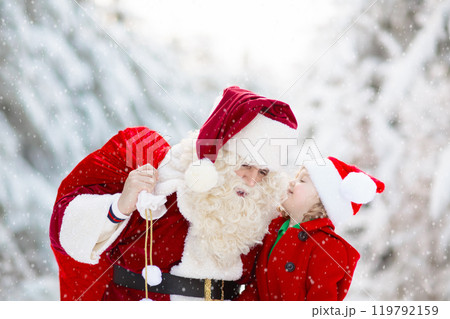 Kids and Santa with Christmas gifts in snow forest 119792159
