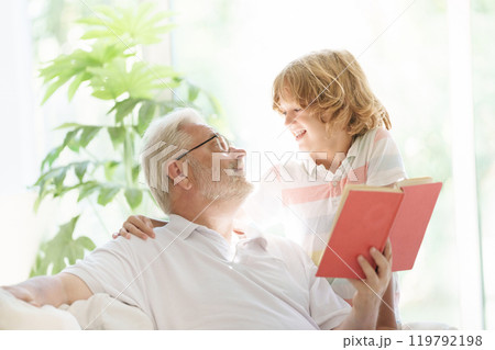 Grandfather and kids read book at home. Grandfather and kids read book at home. 119792198