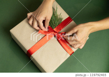 a female hands with a burgundy manicure holds a gift box with a red bow 119792403