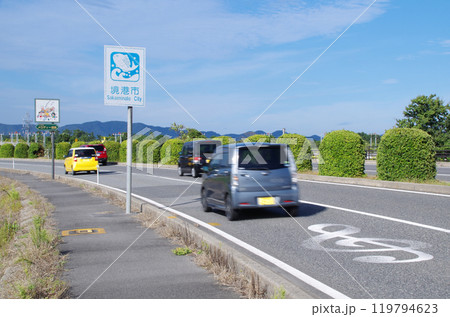 鳥取県境港市の米子鬼太郎空港沿いのメロディー道路を自動車が次々と通過する光景 119794623