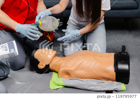 Woman holding breathing bag Ambu bag.Demonstrating CPR Cardiopulmonary resuscitation training medical procedure on CPR doll in the class.Paramedic demonstrate first aid practice for save life Woman holding breathing bag Ambu bag.Demonstrating CPR Cardiopulmonary resuscitation training medical procedure on CPR doll in the class.Paramedic demonstrate first aid practice for save life 119795977