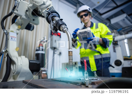 Close up head welding machine robot arm Industry. Technician engineer using remote control automation robotics at industrial modern lab factory. Close up head welding machine robot arm Industry. Technician engineer using remote control automation robotics at industrial modern lab factory. 119796191