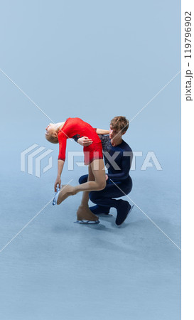 Professional ice skating partners, man and woman, perform difficult lift as part of their routine against cold blue background. 119796902