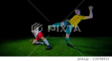 Soccer player's powerful kick mid-action, demonstrate athletic energy and focus in competitive match on green football field against black studio background. Soccer player's powerful kick mid-action, demonstrate athletic energy and focus in competitive match on green football field against black studio background. 119796914