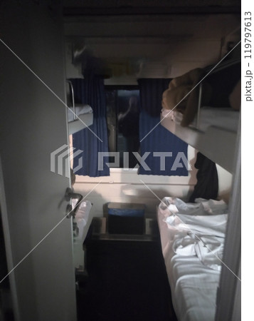 Train cabin with bunk beds, curtains, and window in a sleeper compartment. Train cabin with bunk beds, curtains, and window in a sleeper compartment. 119797613