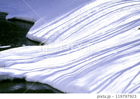 川沿いの雪に描かれた木の影の模様 川沿いの雪に描かれた木の影の模様 119797923