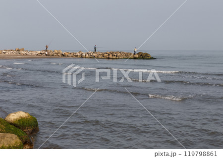 Fishermen stand on the shore and catch fish with a fishing rod. Caspian Sea, Iran Fishermen stand on the shore and catch fish with a fishing rod. Caspian Sea, Iran 119798861
