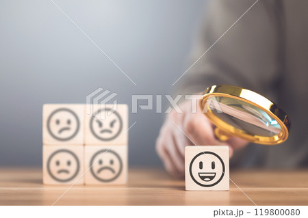 A man choosing between a happy and sad face on wooden blocks, ultimately selecting the happy one. The concept of starting each day with positivity, emphasizing the importance of a bright outlook A man choosing between a happy and sad face on wooden blocks, ultimately selecting the happy one. The concept of starting each day with positivity, emphasizing the importance of a bright outlook 119800080