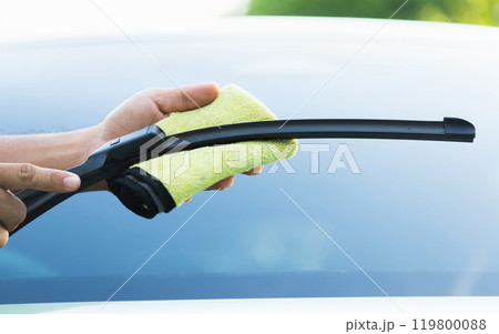 Car owner cleans the windshield wipers with a cloth, highlighting the importance of regular maintenance for optimal performance and clear visibility in all weather conditions Car owner cleans the windshield wipers with a cloth, highlighting the importance of regular maintenance for optimal performance and clear visibility in all weather conditions 119800088