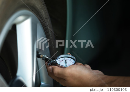Car owner uses a pressure gauge to check tire inflation, emphasizing vehicle readiness and the importance of proper tire maintenance before embarking on a journey Car owner uses a pressure gauge to check tire inflation, emphasizing vehicle readiness and the importance of proper tire maintenance before embarking on a journey 119800108