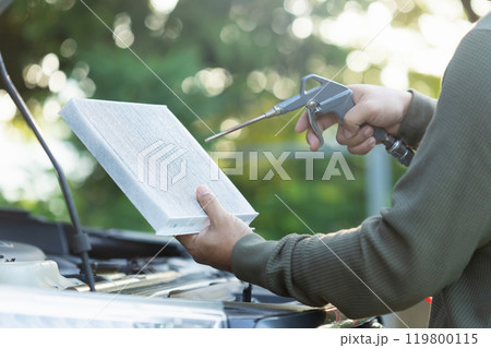 Car owner holds an air filter for examination. Importance of regular inspection, cleaning, and replacement of car air filters, Emphasizes maintenance for better air quality and vehicle efficiency Car owner holds an air filter for examination. Importance of regular inspection, cleaning, and replacement of car air filters, Emphasizes maintenance for better air quality and vehicle efficiency 119800115