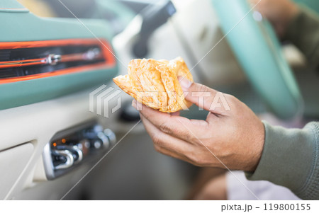 Car owner enjoys a pie while seated inside. Highlighting the impact of food scents in car interiors, Reflects the experience of eating on the go and its effect on cabin air quality Car owner enjoys a pie while seated inside. Highlighting the impact of food scents in car interiors, Reflects the experience of eating on the go and its effect on cabin air quality 119800155
