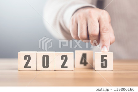 Hand replaces "2024" with "2025" using number blocks, symbolizing the transition into the new year, representing change, progress, and the ongoing passage of time Hand replaces "2024" with "2025" using number blocks, symbolizing the transition into the new year, representing change, progress, and the ongoing passage of time 119800166