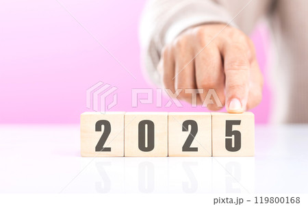 Hand replaces "2024" with "2025" using number blocks, symbolizing the transition into the new year, representing change, progress, and the ongoing passage of time 119800168