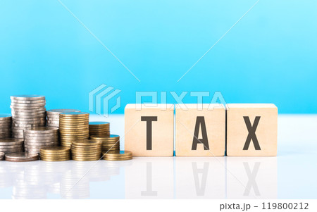 TAX is write on a wooden block next to a stack of coins. Against light blue background. Tax awareness, financial planning, savings, and effective money management TAX is write on a wooden block next to a stack of coins. Against light blue background. Tax awareness, financial planning, savings, and effective money management 119800212