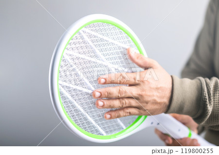 A Man is holding the swatter and touching its circuit, Whether it poses a physical danger to the human body. Concept explores whether a person can touch the circuit of an electric mosquito swatter 119800255