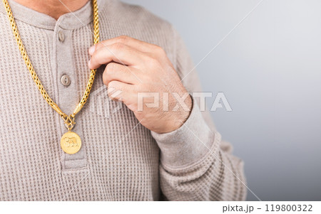 A close-up of a man wearing a gold necklace, symbolizing market speculation. Represents the concept of tracking gold prices, highlighting the connection between personal investment and market trends A close-up of a man wearing a gold necklace, symbolizing market speculation. Represents the concept of tracking gold prices, highlighting the connection between personal investment and market trends 119800322