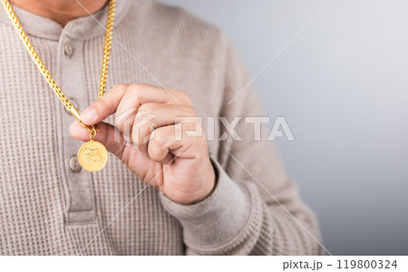 A close-up of a man wearing a gold necklace, symbolizing market speculation. Represents the concept of tracking gold prices, highlighting the connection between personal investment and market trends 119800324