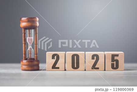 A wooden block displaying '2025' sits beside an hourglass, symbolizing the passage of time and anticipation for the future. Concepts of new beginnings, planning, and the countdown to what's ahead 119800369