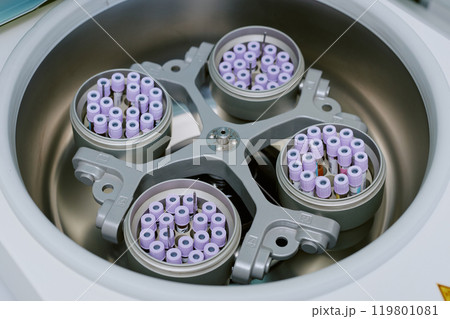 Detailed close-up of biological sample tubes being spun in high-speed laboratory centrifuge. Image captures top view of device displaying balanced tube holders Detailed close-up of biological sample tubes being spun in high-speed laboratory centrifuge. Image captures top view of device displaying balanced tube holders 119801081