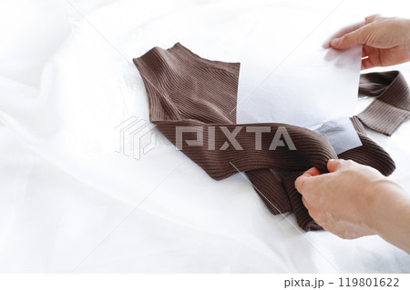 購入したセーターをビニール袋から出す女性の手元素材 119801622