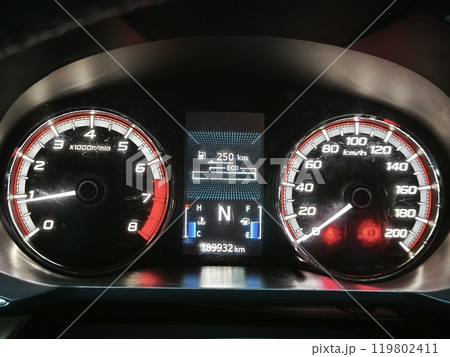 A car dashboard with a digital display, ECO mode indicator, and a tachometer. 119802411