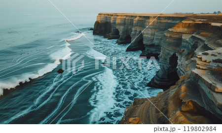 A magical seaside cliff where waves crash in mesmerizing patterns, creating a breathtaking spectacle. 119802984