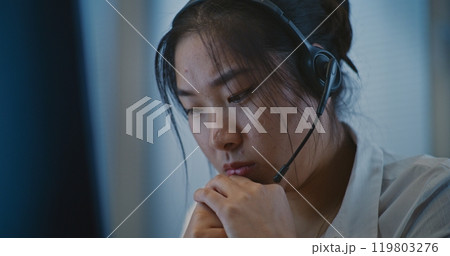 Psychological hotline: Asian helpline specialist in headset listening person 119803276