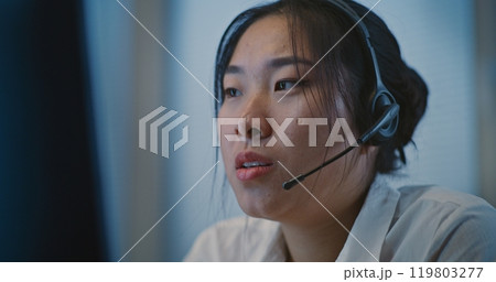 Psychological hotline: Asian helpline specialist in headset listening person 119803277