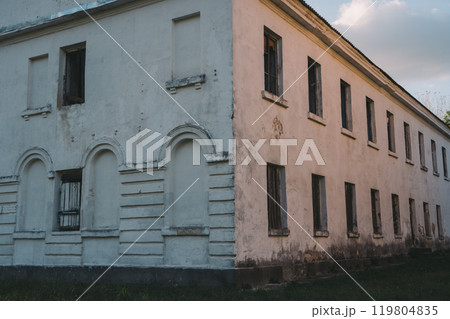Boarded-up windows of an old abandoned building. Evening sunlight 119804835