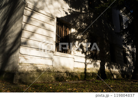 Boarded-up windows of an old abandoned building. Evening sunlight 119804837