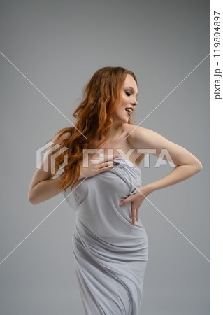 Model poses elegantly in a silver outfit against a neutral backdrop 119804897