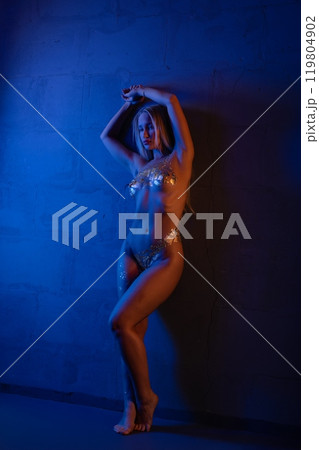 A dancer poses dramatically under blue light in an artistic studio setting 119804902