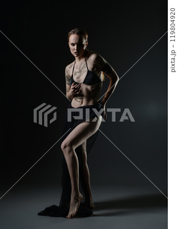 Model posing dramatically in dark studio with flowing fabric at twilight 119804920
