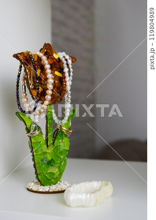 A flowershaped holder organizes necklaces and rings on a table 119804989