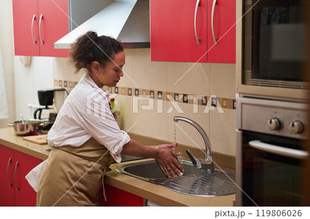 Woman washing hands at kitchen sink with red cabinets Woman washing hands at kitchen sink with red cabinets 119806026