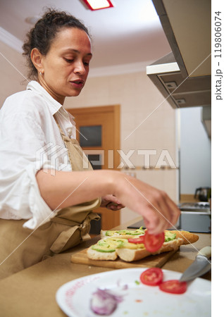 Woman preparing fresh vegetable sandwiches in a modern kitchen 119806074